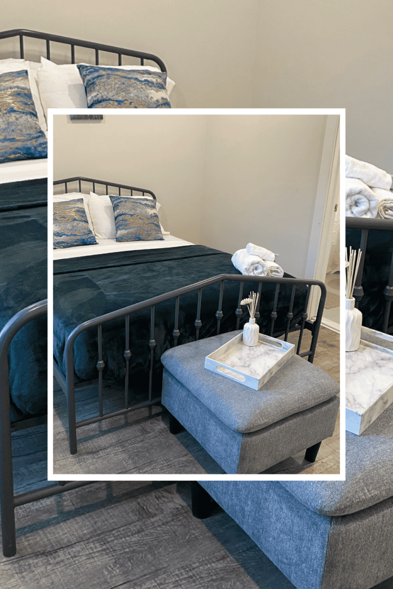 Modern bedroom featuring a black metal bed frame, plush pillows, and a cozy ottoman with decorative.