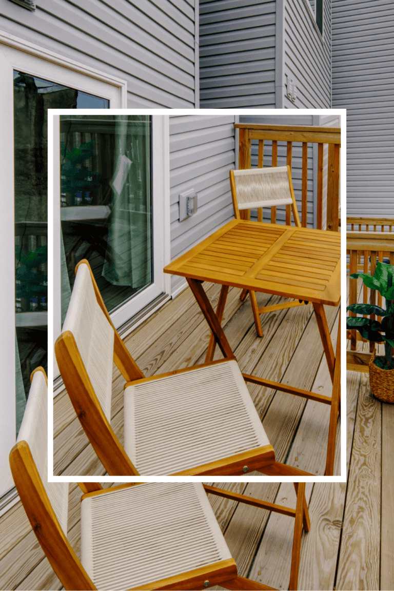 Outdoor wooden dining set on a balcony with a view of the house exterior.