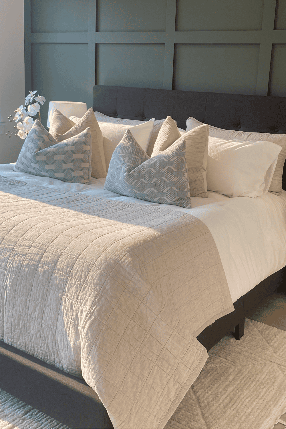 Elegant bedroom with plush pillows, soft bedding, and contemporary wall paneling.